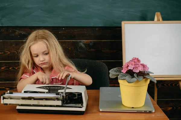 Pequeña niña tipo resultado de la investigación en la máquina de escribir. Trabajo de investigación de escritura infantil en el aula —  Fotos de Stock