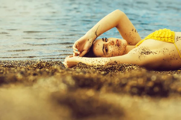 海のビーチで寝ている黄色の水着でかわいい女の子 — ストック写真