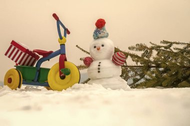 Kardan adam ve köknar ağacı üzerinde beyaz sky. Üç tekerlekli bisiklet karlı zemin üzerine mevcut kutusuyla. Noel ve yeni yıl kutlama. Xmas sürpriz ve hediyeler. Kış tatil kavramı