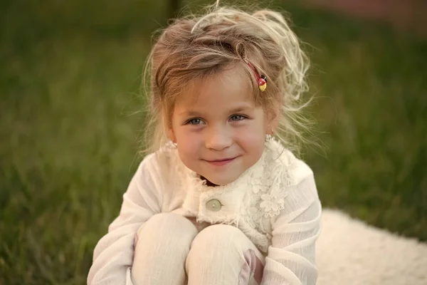 Menina com cabelo loiro bonito sorriso sentar na grama verde — Fotografia de Stock