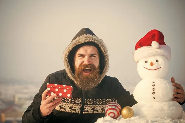Uomo felice e pupazzo di neve in cappello di Babbo Natale sul cielo grigio — Foto Stock