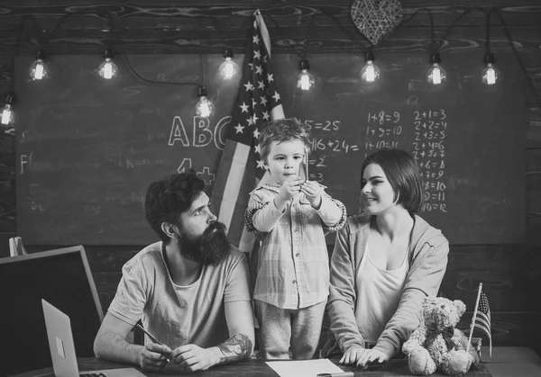 미국 국기와 함께 교실, 칠판 배경에서 부모와 아이. 미국 가족의 아들 및 미국 국기와 함께 책상에 앉아. 애국적인 교육 개념입니다. 부모 교육 아들 미국 전통 재생 — 스톡 사진