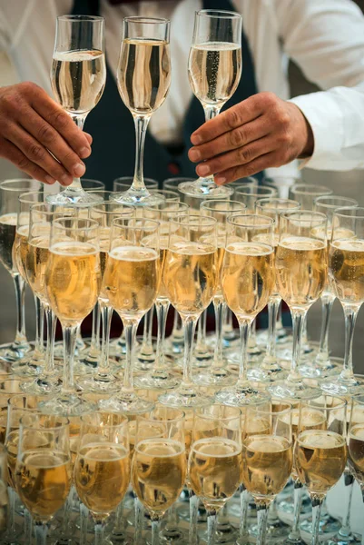 Champagne lifestyle. Champagne and sparkling wine glasses. Champagne tower of flute glasses. Serving champagne or wine at drink reception. Celebrate holiday with alcoholic drink