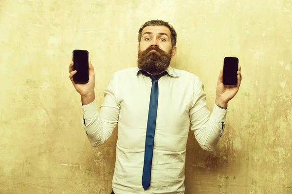Gerente ou homem barbudo comparar telefone celular e smartphone — Fotografia de Stock