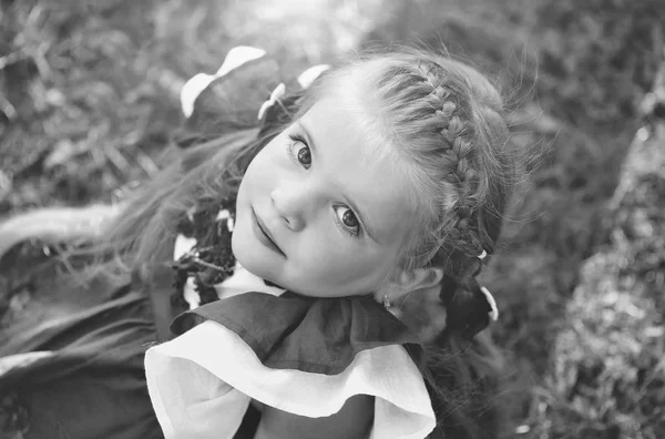 Menina bonito feliz com cabelo de trança sorrindo na grama verde — Fotografia de Stock