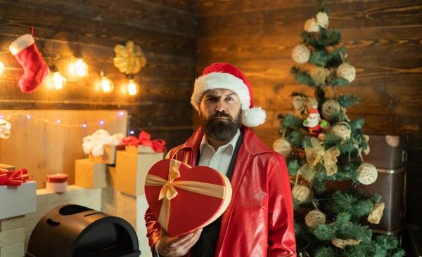 Homem de Natal na moda vestido vermelho. Papai Noel barbudo deseja Feliz Natal e Feliz Ano Novo. Papai Noel com caixa de presente de Natal vermelho. — Fotografia de Stock