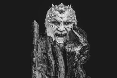 adam ya da dikenler yüzünde sakal ve tree yakınındaki siyah arka plan üzerine gözünde lens ile yabancı olarak fütüristik makyaj ile ile öfkeli canavar