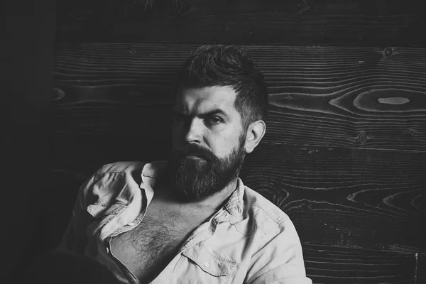 Sérieux hipster dans le salon de coiffure, regarde. Coupe de cheveux d'homme barbu, archaïsme. Mode et beauté masculine de l'homme grisonnant. Salon de coiffure et de coiffure. Homme barbe et moustache sur fond bois . — Photo