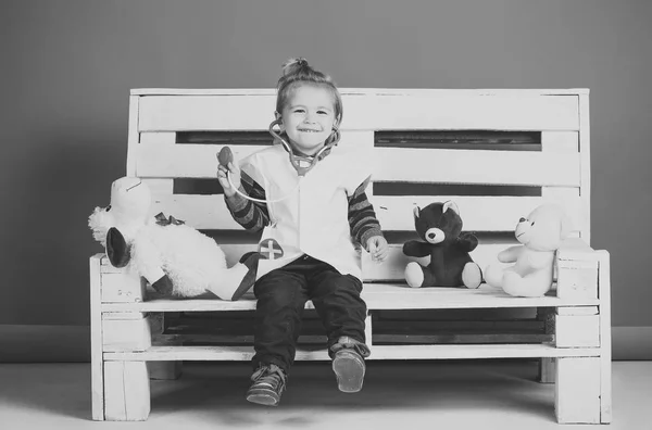 Enfant heureux avec jouets animaux de compagnie assis sur un banc en bois — Photo