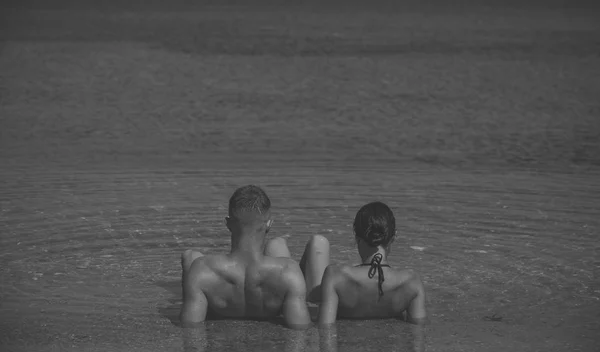 Casal feliz relaxante, bronzeamento na praia, deitado na água, olhando para o oceano, copyspace. Conceito de lua de mel e férias. Casal apaixonado relaxando em férias, lua de mel. Jovens amantes nadam no mar . — Fotografia de Stock