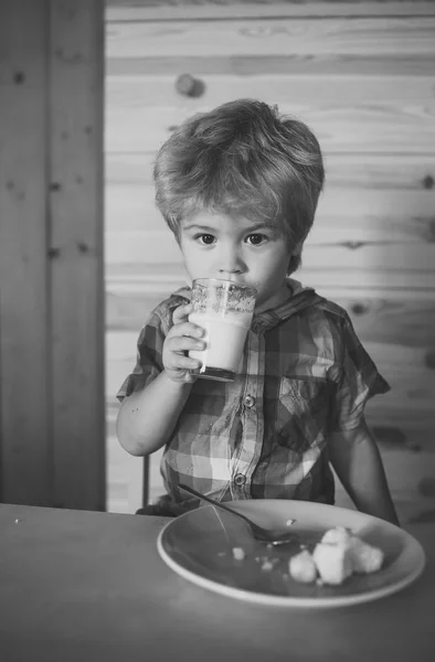 Small boy child eat banana and drink milk.