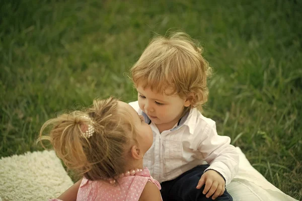 Irmã beijo irmão com cabelo loiro na grama verde — Fotografia de Stock