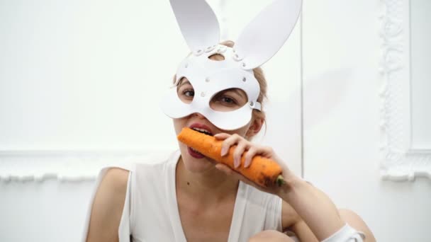 Woman wearing a mask eats carrots. sexy girl in mask concept. — Stock Video