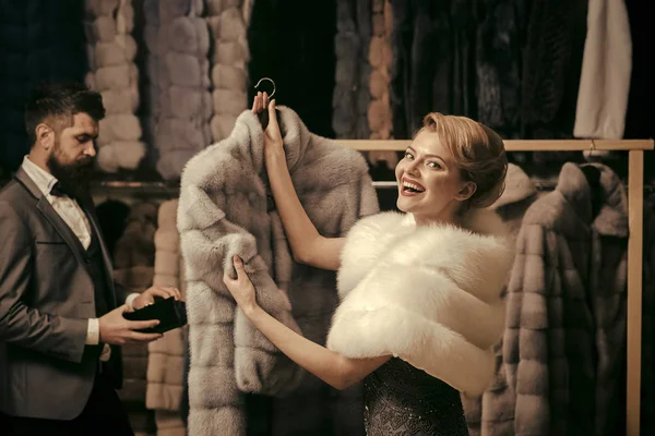 Homme au visage strict et femme avec des manteaux dans un magasin de fourrure . — Photo