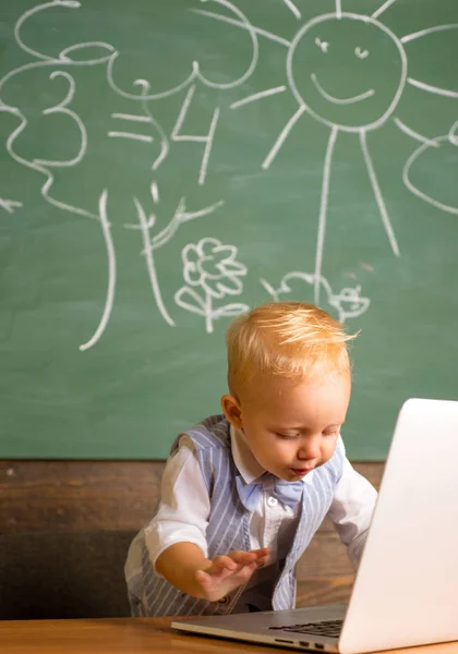 Little boy enjoy virtual world of internet in school. Toddler explore virtual world with laptop in classroom
