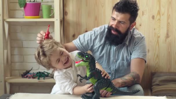 Vader en zoon spelen speelgoed dinosaurussen. Dag van vader en zoon. Gelukkig vader speelt met zijn zoon in een spel van dinosaurussen. vader en schattig zoontje spelen met diverse speelgoed dinosaurussen samen thuis. — Stockvideo
