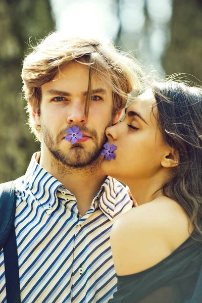 Joven hombre con chica celebrar flor en la boca —  Fotos de Stock