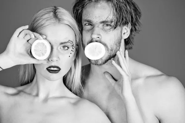 woman and man with makeup hold lemon