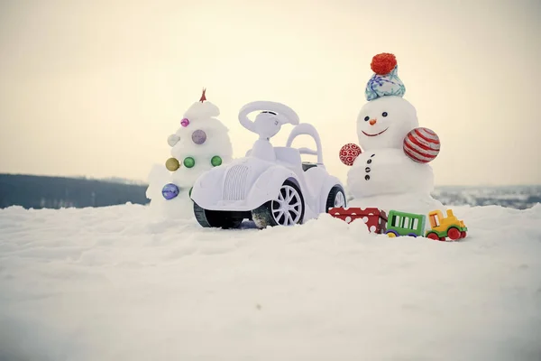 Toy car and snowman on snowy background