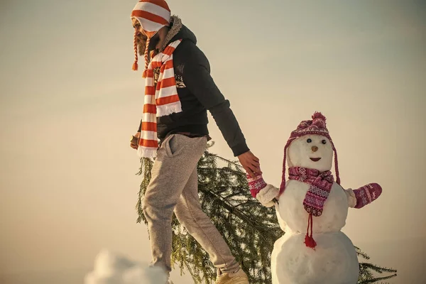 Guy and snow sculpture wearing hats and scarves — Stock Photo, Image