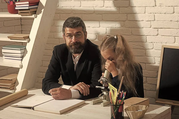 stock image Girl and man sit at desk and look into microscope