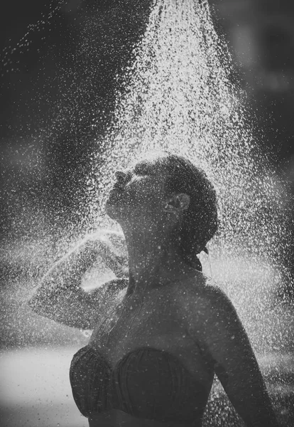 Jeune belle fille brune prenant douche sur la plage après la baignade. Dame sexy en bikini bénéficie d'une douche par temps chaud et ensoleillé. Concept de chauffage et de rafraîchissement. gouttes d'eau tombant sur la femme attrayante . — Photo