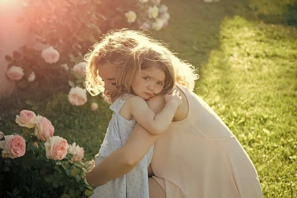 Kvinna med flicka barn på blommande ros blommor — Stockfoto