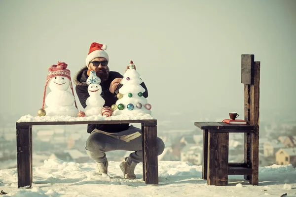 Man in glazen versieren sneeuw kerstboom op blauwe hemel — Stockfoto