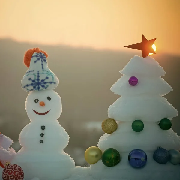Sneeuwpop met smiley gezichten in de hoed op avond landschap — Stockfoto