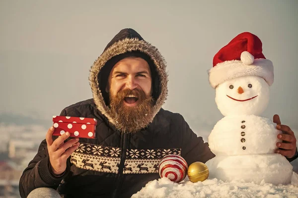 Felice hipster e pupazzo di neve in cappello di Babbo Natale sul cielo grigio — Foto Stock