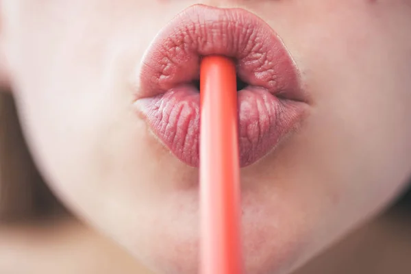 Trinktag. Schluck für Schluck durch Stroh. weibliche Lippen beim Trinken mit Stroh. Trinkrohr ist ein kleines Rohr, um ein Getränk zu konsumieren. orangefarbenes Kunststoffrohr. Trinkhalm im Mund — Stockfoto