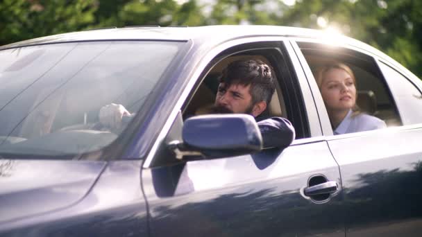 Hipsters barbudos y rubia viajan en coche. Conductor barbudo y mujer atractiva están sentados en un coche azul. Concepto de viajar en coche . — Vídeo de stock