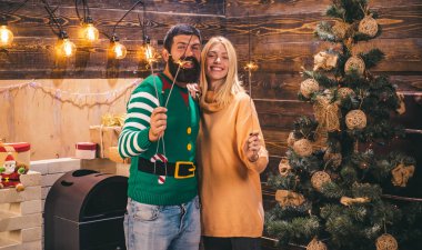 Yılbaşı süsleri ve hediye kutusu ahşap arka plan üzerinde. Sevimli genç kadın ve santa şapka ile yakışıklı adam. Noel elbiseler.