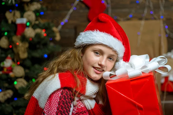 Retrato de adolescente presente de Natal. Menina bonito está decorando a árvore de Natal dentro de casa. Adolescente alegre olhando para a câmera no Natal em casa. Menina feliz com caixa de presente de Natal . — Fotografia de Stock