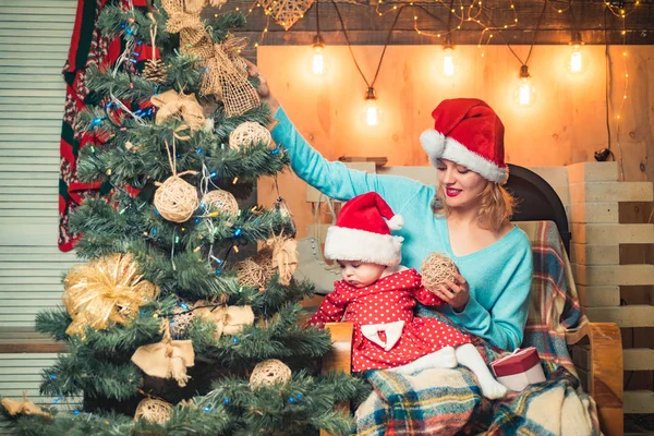 Праздник и единение у елки. С Рождеством и Новым годом. Мама и дочь украшают елку. Рождественская семья . — стоковое фото