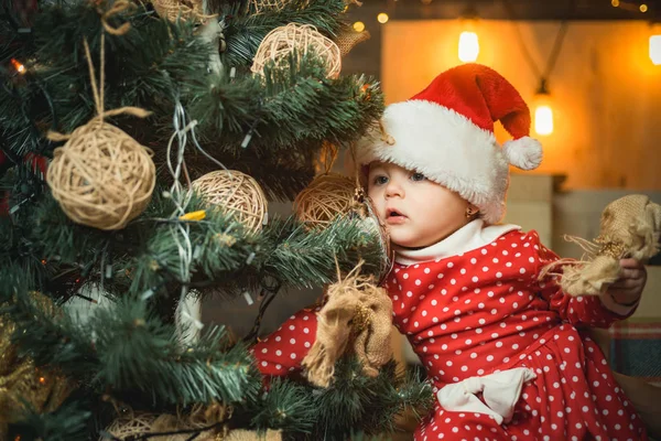 Kind schmücken den Weihnachtsbaum auf Holzuntergrund. Glückliche Kinder. Weihnachtsbabys. Niedliches kleines Kind schmückt Weihnachtsbaum drinnen. — Stockfoto