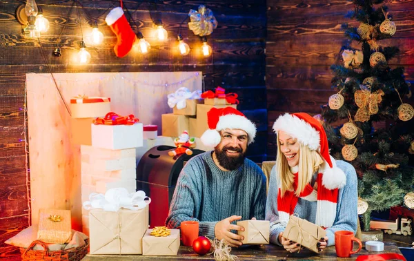 Söt ung kvinna och stilig man med santa hatt. Kärlek. Nytt år familj med jul nuvarande lådor framme med julgran. Christmas par. Julgran dekorera hemma. — Stockfoto