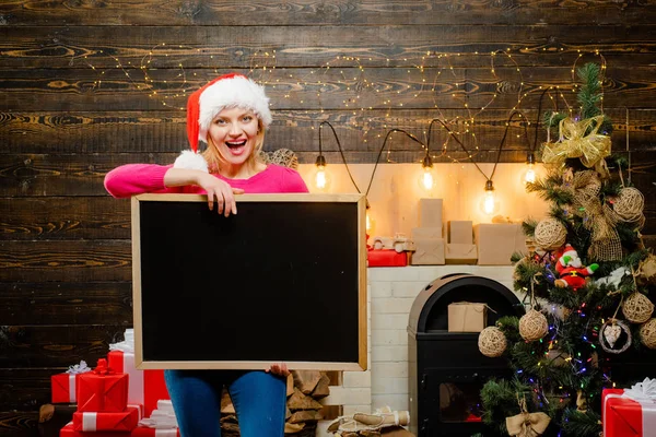 Préparation de Noël. Femme de Noël tenant un bureau noir pour le texte. Espace de copie du tableau noir. Jolie fille en robe de Noël. Belle femme du Père Noël. Sexy Santa Clause femme dans élégant — Photo