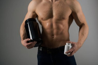 Transforming body with diet. Anabolic hormone increases muscle strength. Strong man hold vitamin bottles. Man with six pack abs. Muscle growing with anabolic steroids. Vitamin nutrition. Healthy diet clipart