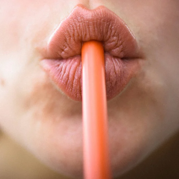 Sip of freshness. Drinking straw in mouth. Sipping drink through straw. Female lips while drinking with straw. Drinking straw. Drinking tube is a small pipe to consume a beverage. Orange plastic tube