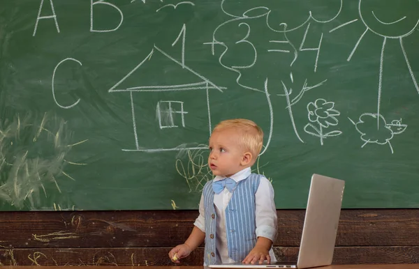Маленький хлопчик з ноутбуком у комп'ютерному класі. Користувач ноутбука вивчає нову технологію в школі. Досвід інформаційних технологій — стокове фото