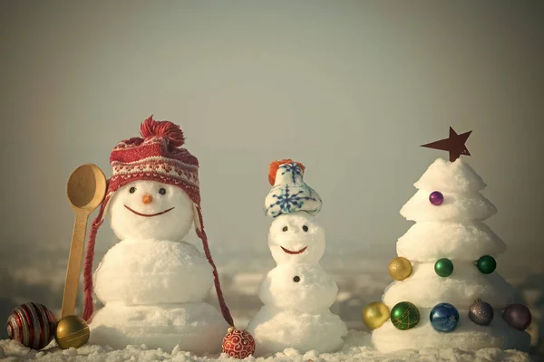 Muñecos de nieve con caras sonrientes en sombreros en el día de invierno — Foto de Stock