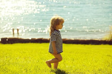 Şirin bebek çocuk çizgili tshirt yeşil çimenlerin üzerinde yürüyor