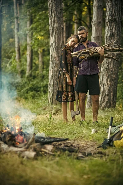 Woman hug man lumberjack with axe and bunch of firewood