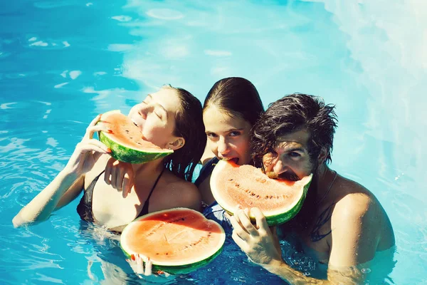 Vrouwen en man met watermeloen in zwembad — Stockfoto