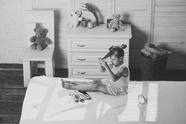 Barnet sitter på sängen med ljusa läppstift och kosmetika i childroom — Stockfoto