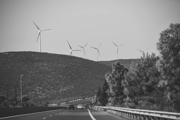 Windmills, wind generators on hill, mountain. Landscape with mountains, roads, trails, cars. Alternative energy sources concept. Giant white windmills on mountains. — Stock Photo, Image