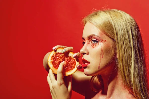 Hübsche blonde Frau mit kreativem modischem Make-up halten Grapefruit, Vitamin — Stockfoto
