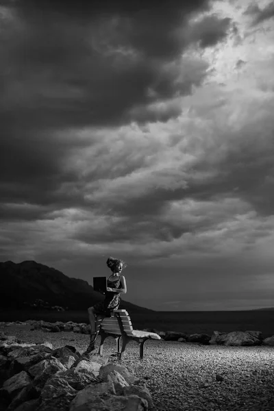 Femme avec ordinateur portable sur la plage du soir — Photo