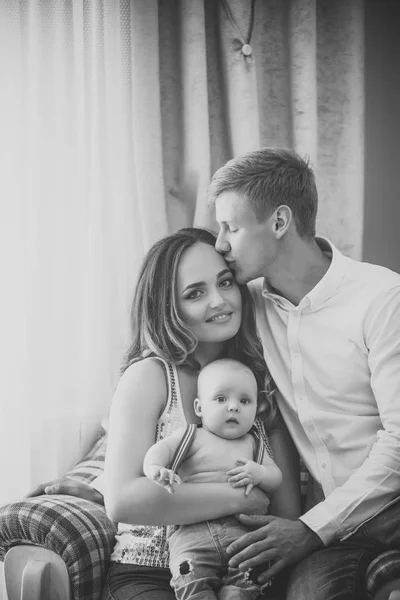 Far kiss mor med baby son i fåtölj — Stockfoto